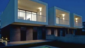 A modern building with large windows and a pool in the foreground.