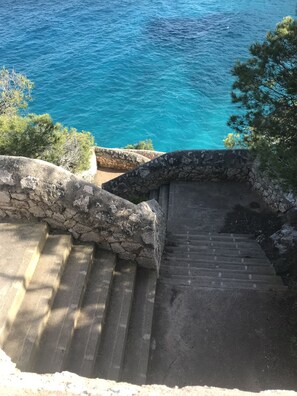 Eine steile Steintreppe führt zu einer Küstenregion mit Blick auf das Meer.