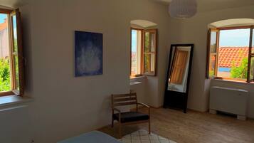 Una stanza con un letto, una sedia, un quadro e una finestra vista edifici.