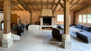 A rustic cabin interior with a stone fireplace, wooden beams, a drum set, and a sofa. - Maison Type Grange (Andernos les Bains)