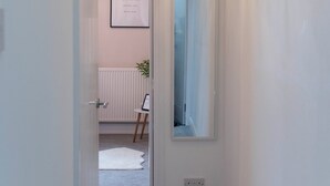 Un couloir orné d’un lustre, avec une citation inspirante encadrée au mur et un miroir qui reflète une porte.