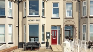 Une rangée de maisons de ville avec une enseigne bien visible portant l’inscription « HIGHCLIFFE » sur la façade.