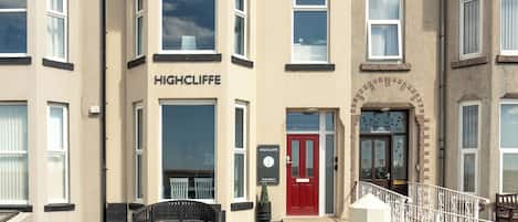 Une rangée de maisons de ville avec une enseigne bien visible portant l’inscription « HIGHCLIFFE » sur la façade.