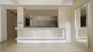 A reception area with a modern design, featuring a central counter and a seating area. - OYO 3743 Gania Hotel (Bandung)