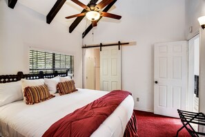 Ein Schlafzimmer mit einem Bett, einem Deckenventilator, einer weißen Tür und einem Fenster mit Jalousien.