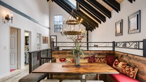 Un espace repas avec une table en bois, des bancs et un banc doté de coussins rouges.