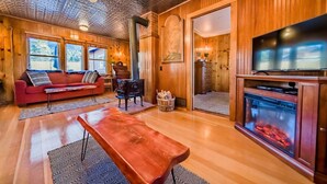 Un salon chaleureux avec un canapé rouge, une table basse en bois, une cheminée et un téléviseur.