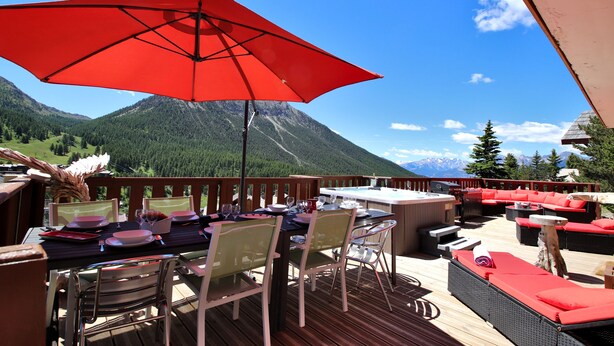 A deck with outdoor seating, a hot tub, and a mountain view.