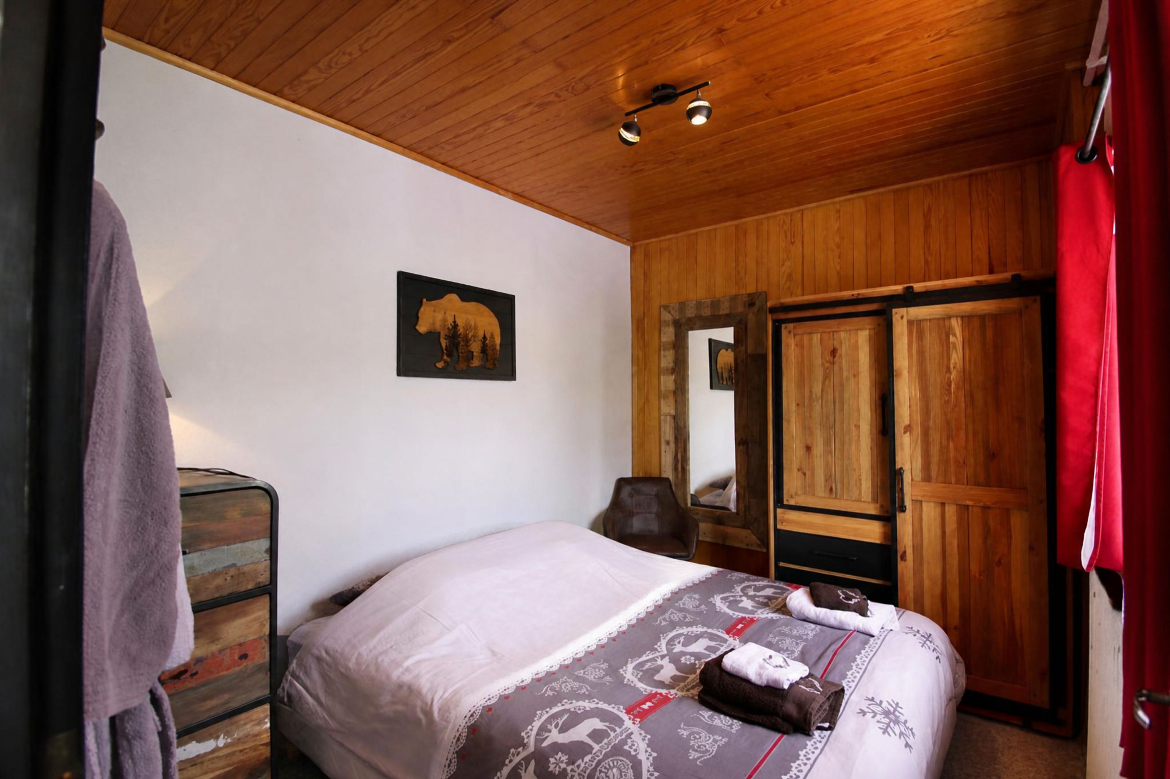 Un dormitorio con cama, armario de madera, espejo y decoración de pared con temática de oso.