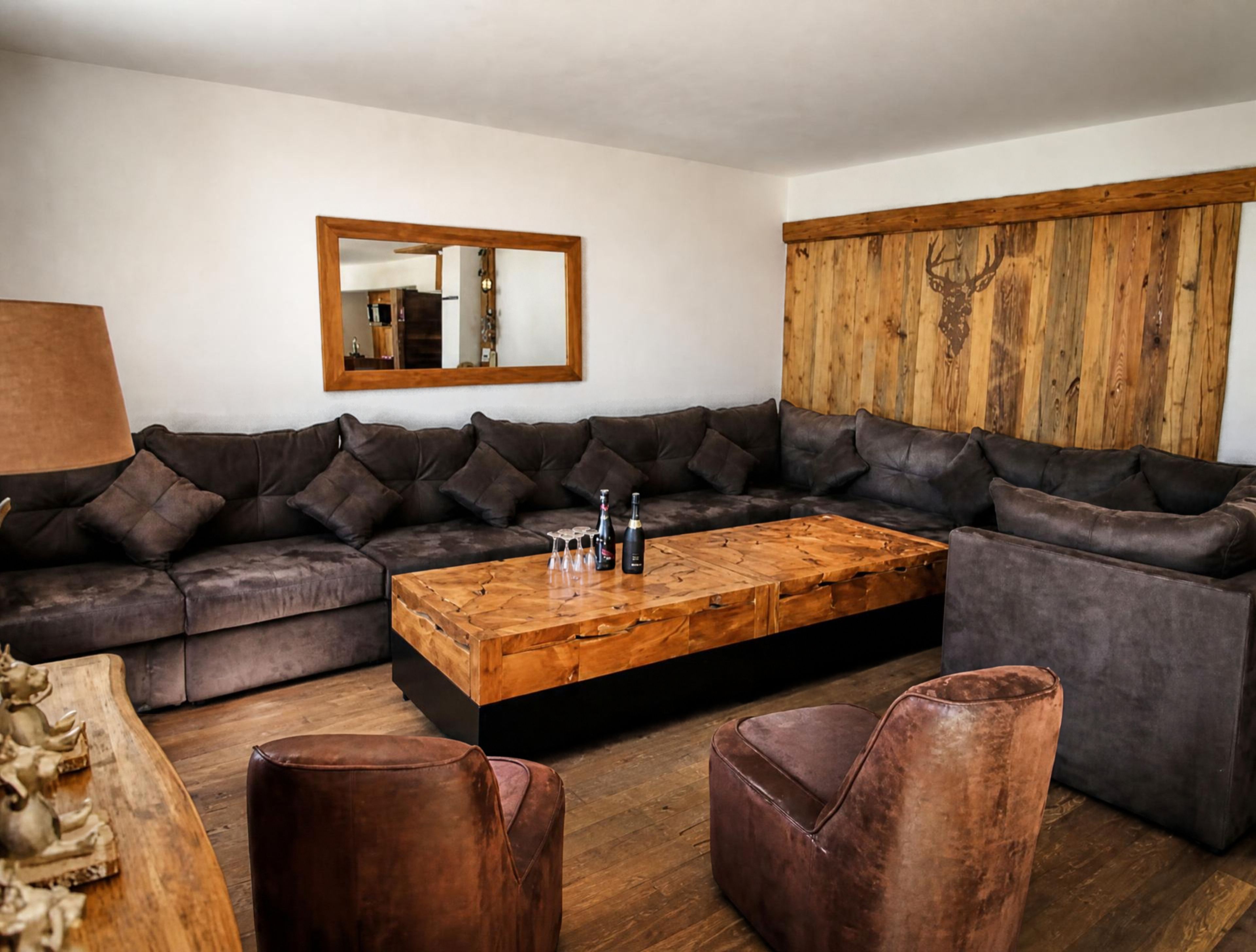 A modern living room with a sectional sofa, a wooden coffee table, and leather ottomans.