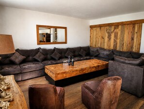 A modern living room with a sectional sofa, a wooden coffee table, and leather ottomans.