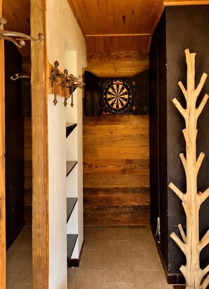 A narrow hallway with wooden walls, a dartboard, and a coat rack. - CHALET FOR 16–18 PEOPLE WITH JACUZZI, SAUNA, MOVIE ROOM, AND VIEWS OF THE SLOPES AND MOUNTAINS (Montgenèvre)