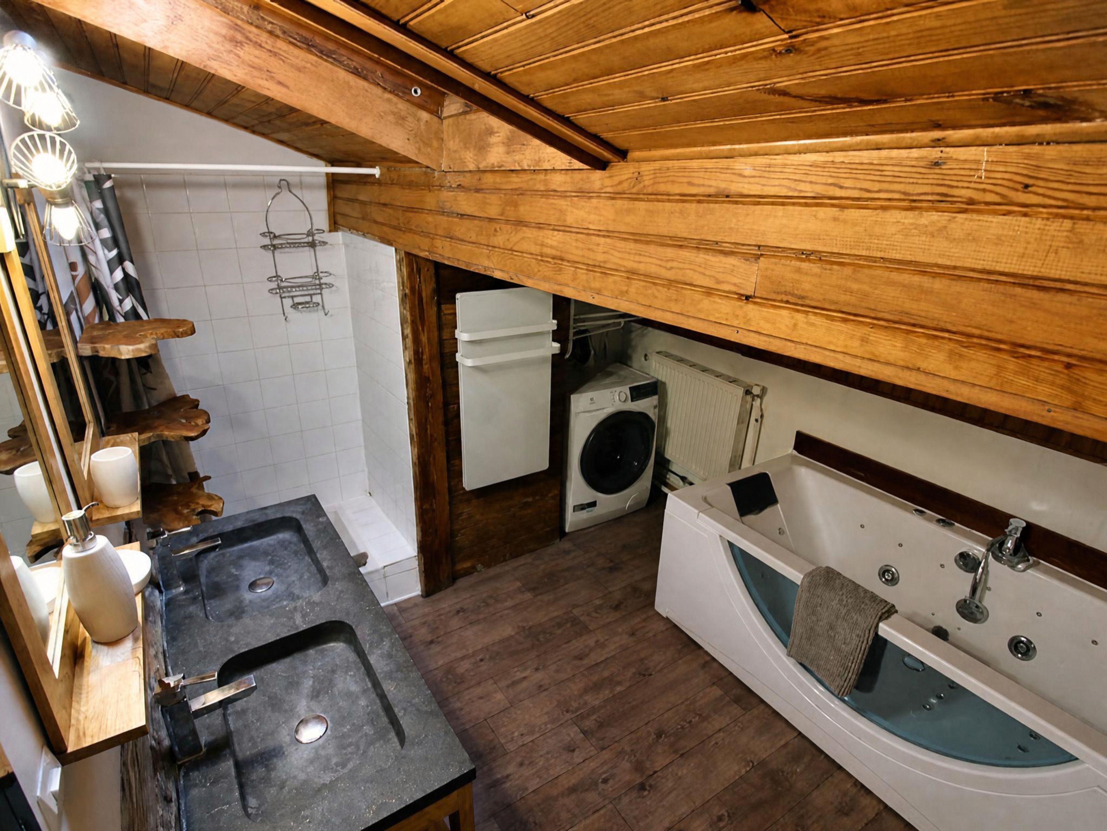 A compact bathroom with a sink, a washing machine, and a bathtub.