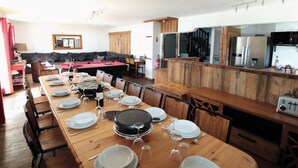 A dining area with a long wooden table set for a meal, a pool table, and a kitchen area with modern appliances.
