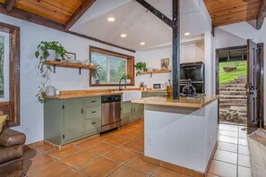 La cuisine est équipée d’un lave-vaisselle, d’un four et d’une machine à café. Une fenêtre offre une vue sur l’extérieur.