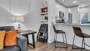 A modern kitchen with white cabinets, a countertop, and a dining area with a table and chairs.