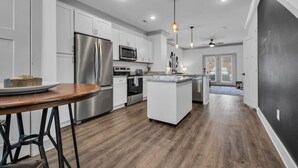 A modern kitchen with stainless steel appliances, a central island, and pendant lighting.