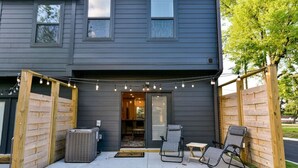A two-story house with a covered patio area featuring outdoor seating and string lights.