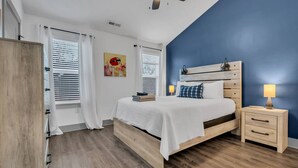 A bedroom with a bed, bedside tables, a ceiling fan, and a window with blinds.