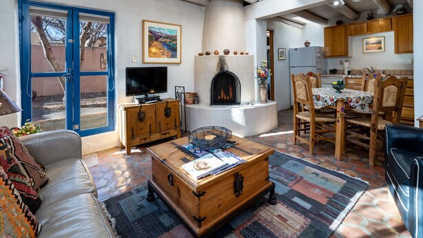 A cozy living room with a fireplace, a television, and a dining area with wooden furniture.