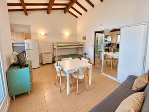 A compact living space with a bunk bed, kitchenette, dining area, and a sofa. - Appartement vue mer et Montagne, à Létage (Calcatoggio)