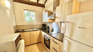 Une cuisine compacte avec des meubles en bois, un four encastré, un évier et un réfrigérateur Bosch.