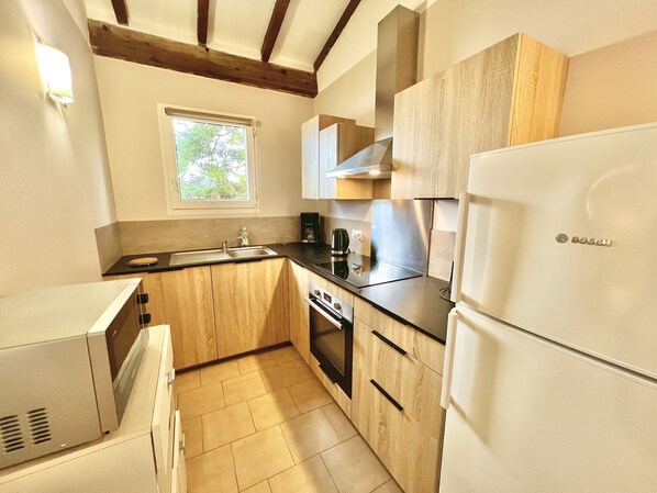 A compact kitchen with wooden cabinets, a built-in oven, a sink, and a Bosch refrigerator. - Appartement vue mer et Montagne, à Létage (Calcatoggio)