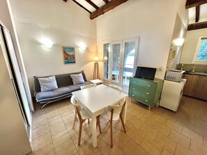A compact living space with a sofa, dining table, and kitchenette. - Appartement vue mer et Montagne, à Létage (Calcatoggio)