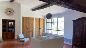 Un salon spacieux avec un canapé blanc, des meubles en bois et une grande fenêtre qui laisse entrer la lumière naturelle.