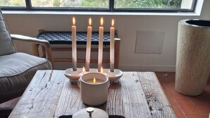 Une table en bois avec un plateau, un chandelier avec des bougies allumées et une vue sur la fenêtre.