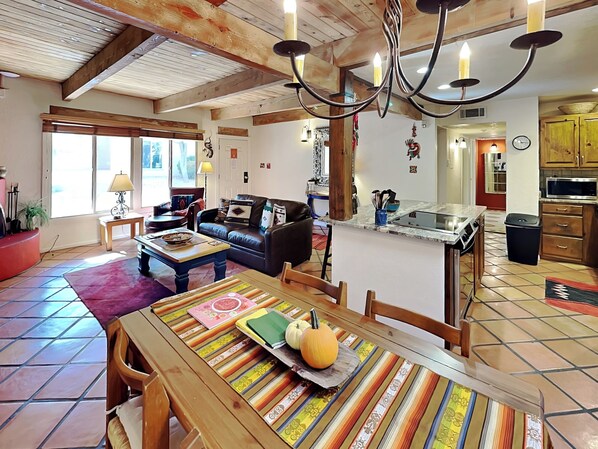 A spacious living area with a dining table, a sofa, and a kitchen in the background. - Artist Rd 7 | Cozy Fireplace, Pool Access, Centrally Located (Santa Fe)