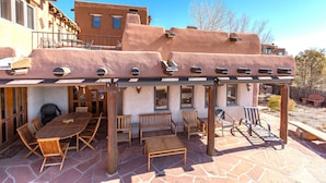 A patio with a stone floor, wooden furniture, and a pergola. - City Views at Alma Compound | Great Location! (Santa Fe)