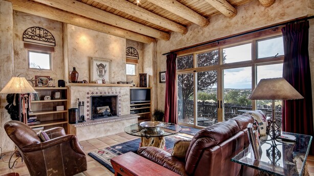 A cozy living room with a fireplace, leather sofas, and a large window offering a scenic view.