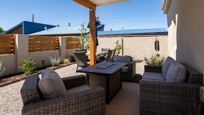 Un espace extérieur aménagé en terrasse, avec des meubles en osier, une table et un barbecue.