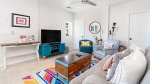 Un salon moderne avec un téléviseur à écran plat, une table basse, un canapé et un fauteuil à rayures.