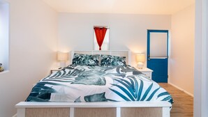 Une chambre à coucher avec un lit, un ventilateur de plafond, une table de chevet avec une lampe et une porte dotée d’un cadre bleu.
