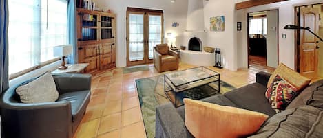 Una sala de estar con sofá, mesa de centro, chimenea, ventilador de techo y estantería.