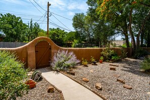 A garden with a curved wall, a wooden gate, and various plants.