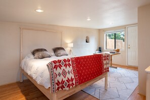 A bedroom with a bed, a bedside table, a lamp, and a window.