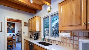 A modern kitchen with wooden cabinets, a stainless steel sink, and a built-in microwave. - Puertas de Canyon Road | Patio, Fenced Yard! (Santa Fe)