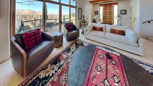 Una sala de estar con ventanas amplias, un sofá, una mesita de centro y un tapete estampado.