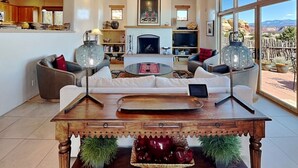 Un salón amplio con chimenea, un ventanal con vistas y techo de madera.
