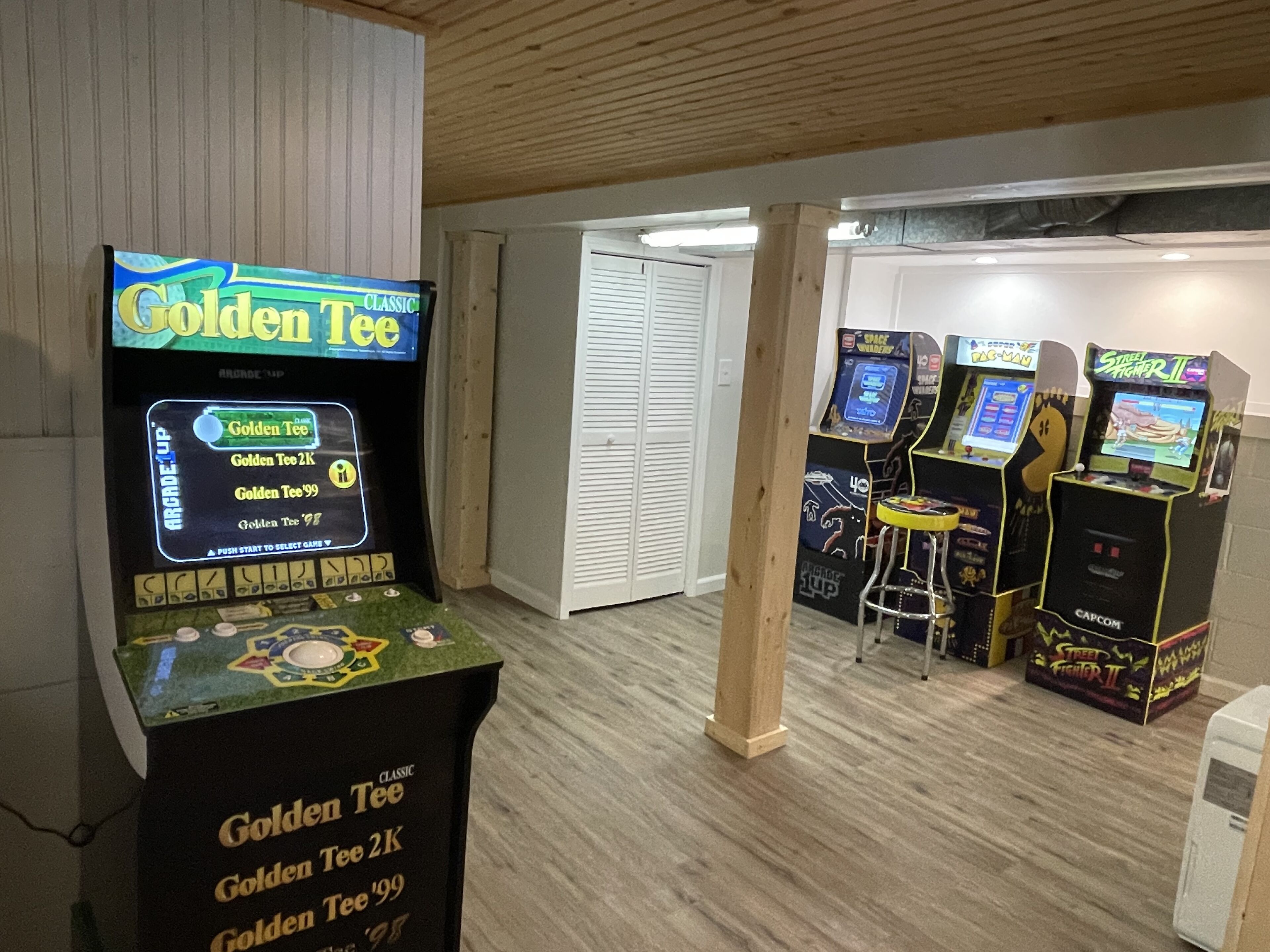 Een kamer met spelautomaten, waaronder 'Golden Tee' en 'Street Fighter II'.