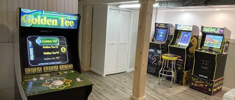 Een kamer met spelautomaten, waaronder 'Golden Tee' en 'Street Fighter II'.