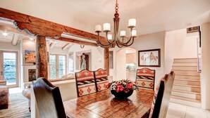 A dining area with a wooden table, chairs, and a chandelier. - El Corazon de Santa Fe | Patios, Private Balcony (Santa Fe)