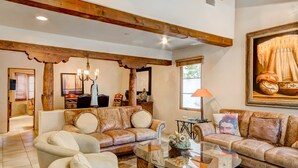 A spacious living room with leather sofas, a glass coffee table, and wooden beams on the ceiling. - El Corazon de Santa Fe | Patios, Private Balcony (Santa Fe)