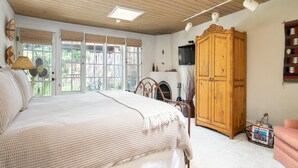 A bedroom with a large bed, wooden ceiling, and a wardrobe.