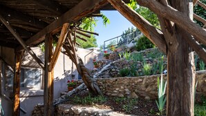 A rustic stone wall with a wooden pergola structure.