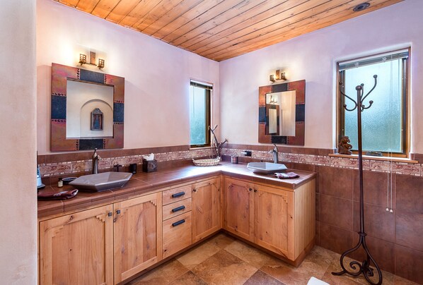 A modern kitchen with wooden cabinets, a large island, and a window with a decorative iron stand.