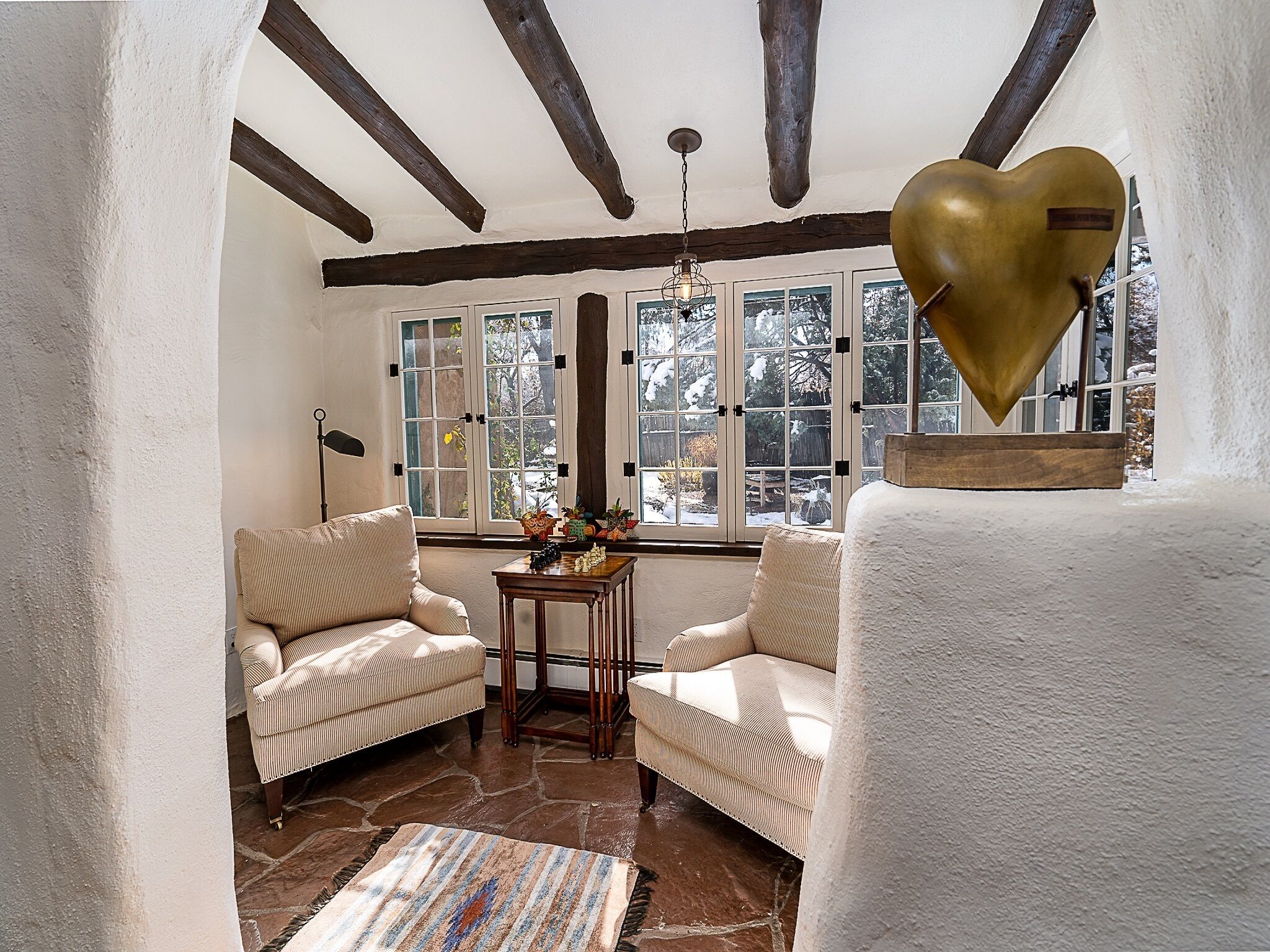 A cozy room with two beige armchairs, a wooden table, and a patterned rug.